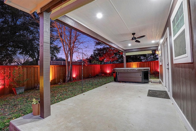 patio terrace at dusk with ceiling fan and a hot tub