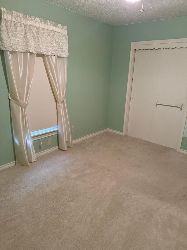 unfurnished bedroom featuring light colored carpet, a textured ceiling, and a closet