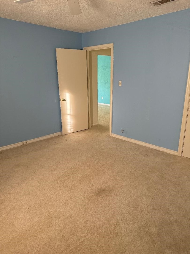 empty room with a textured ceiling, light colored carpet, and ceiling fan