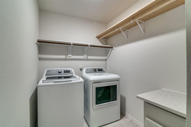 clothes washing area with washer and clothes dryer and light tile patterned floors