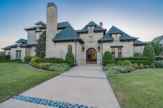 french country inspired facade with a lawn and french doors