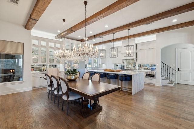 dining space featuring beamed ceiling and wood-type flooring