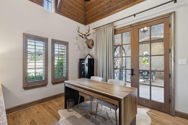 home office featuring lofted ceiling, light wood-type flooring, and french doors