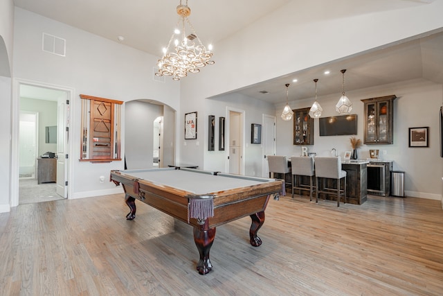 game room with high vaulted ceiling, light hardwood / wood-style flooring, billiards, and bar area