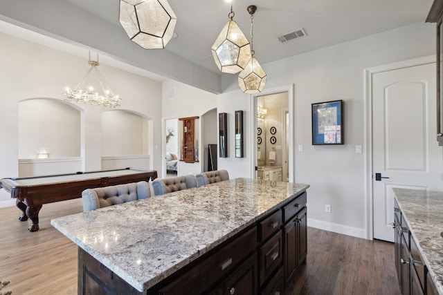 kitchen featuring light stone counters, light hardwood / wood-style flooring, billiards, a kitchen island, and hanging light fixtures