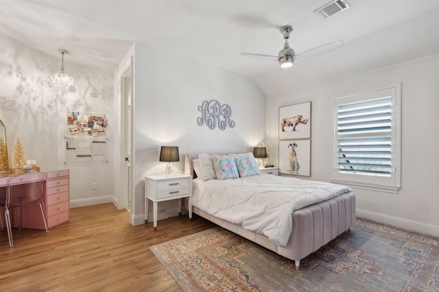 bedroom featuring hardwood / wood-style flooring, ceiling fan with notable chandelier, and lofted ceiling