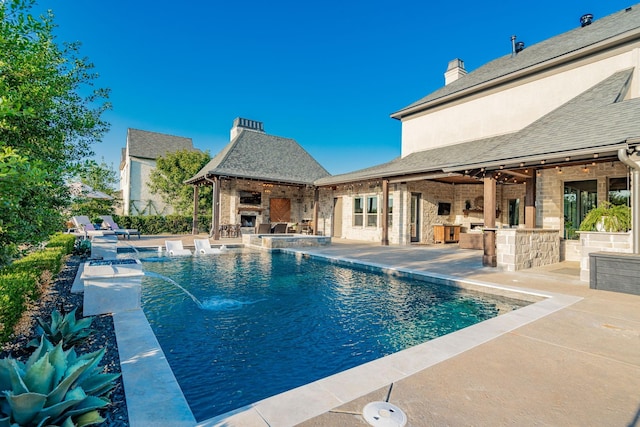 view of pool featuring area for grilling, a patio area, pool water feature, and exterior fireplace