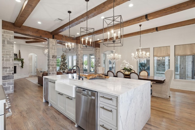 kitchen featuring pendant lighting, white cabinetry, stainless steel dishwasher, and a kitchen island with sink