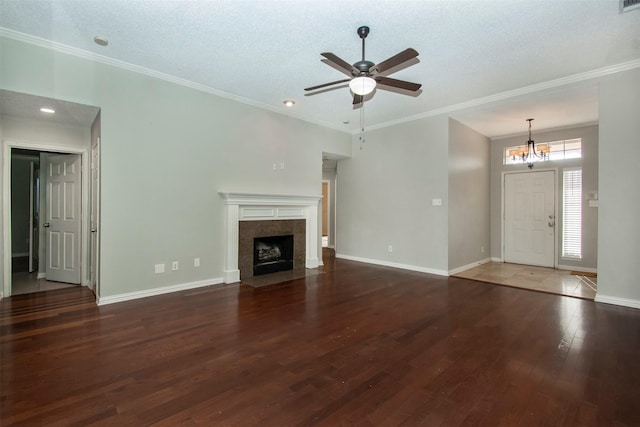 unfurnished living room with ceiling fan with notable chandelier, ornamental molding, a tile fireplace, and dark hardwood / wood-style floors