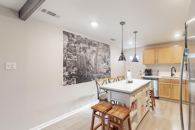 kitchen with light brown cabinetry, light hardwood / wood-style flooring, and stainless steel dishwasher