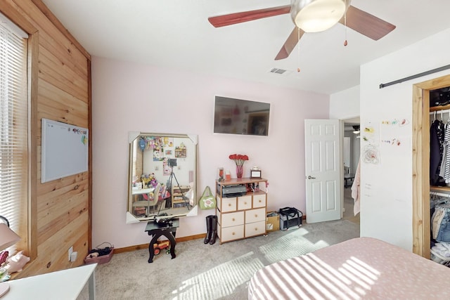 bedroom with light carpet, a closet, ceiling fan, and wooden walls