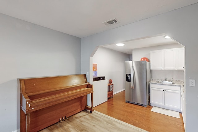 kitchen featuring white cabinets, stainless steel fridge, sink, and light hardwood / wood-style flooring