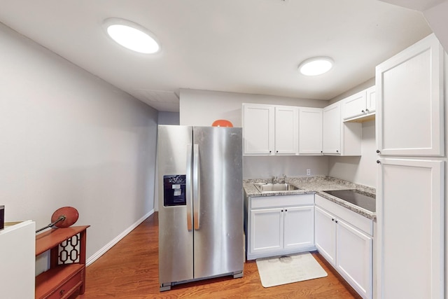 kitchen featuring white cabinets, stainless steel fridge, light hardwood / wood-style flooring, and sink