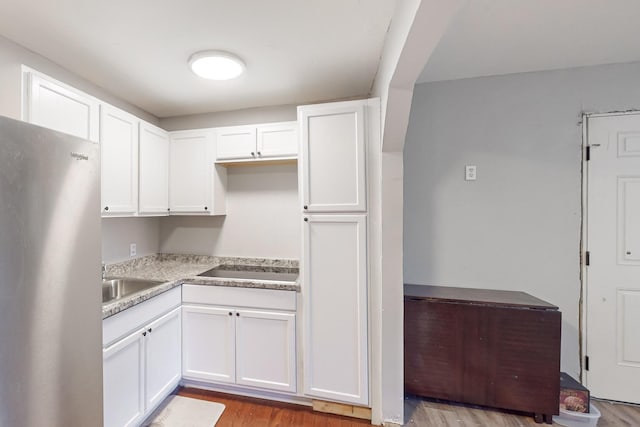 kitchen with white cabinets, stainless steel fridge, and light hardwood / wood-style flooring