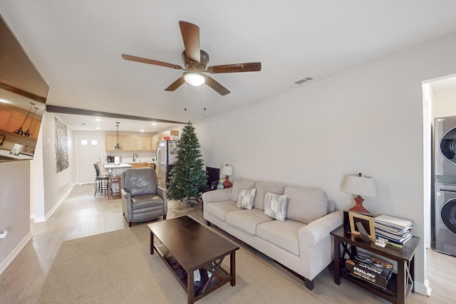 living room with ceiling fan, sink, light hardwood / wood-style flooring, and stacked washer and clothes dryer