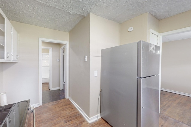 kitchen featuring white cabinetry, stainless steel fridge, a textured ceiling, and hardwood / wood-style flooring