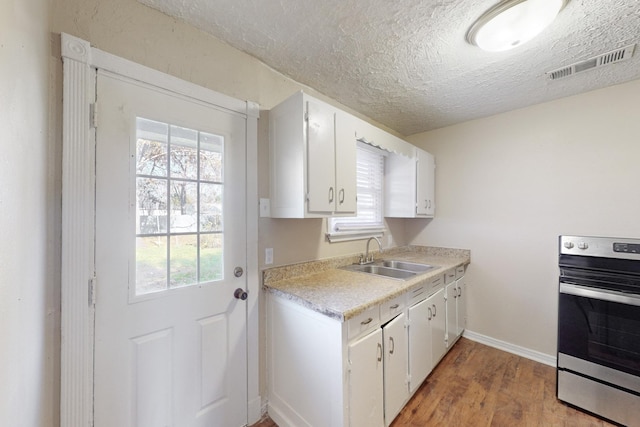 kitchen featuring light wood-type flooring, white cabinetry, wall oven, and sink