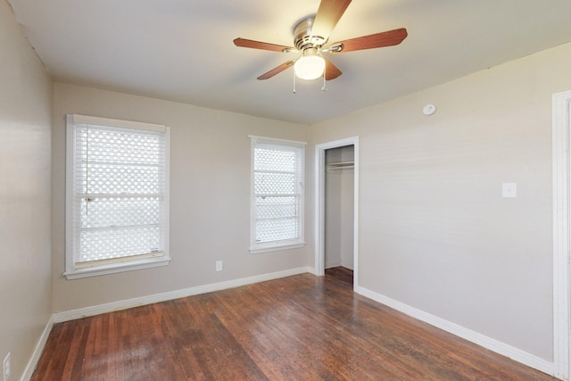 empty room with dark hardwood / wood-style floors, a wealth of natural light, and ceiling fan