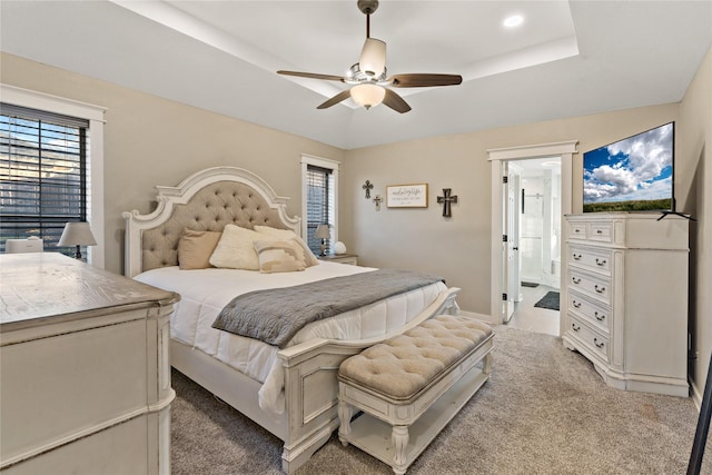 carpeted bedroom featuring a raised ceiling and ceiling fan