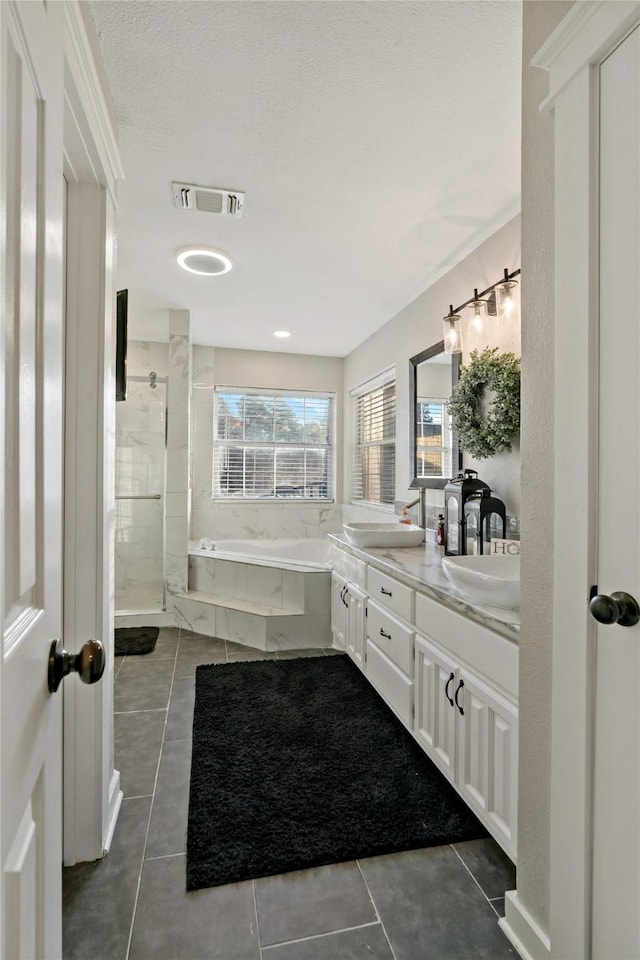 bathroom with shower with separate bathtub, vanity, a textured ceiling, and tile patterned floors