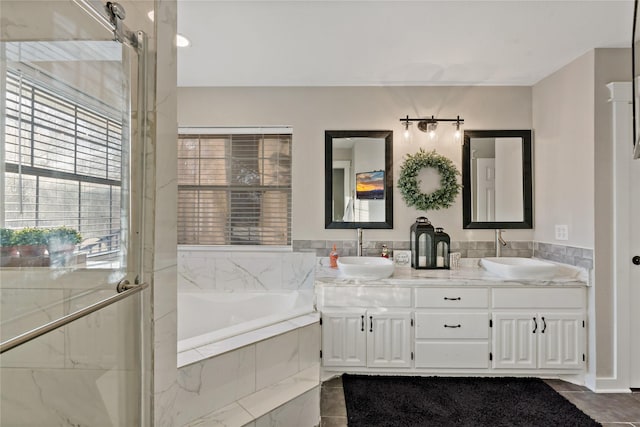 bathroom with tiled tub and vanity