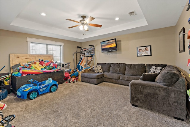 living room with carpet, ceiling fan, and a tray ceiling