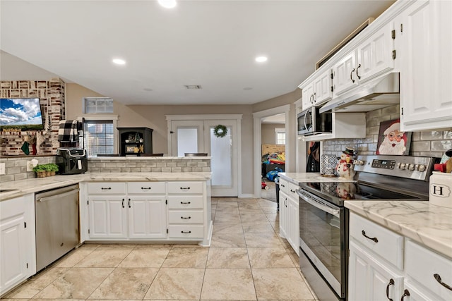 kitchen featuring white cabinets, light stone countertops, stainless steel appliances, and tasteful backsplash