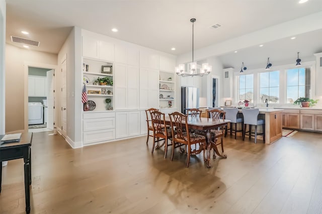 dining space featuring a notable chandelier, light wood-type flooring, and washer / clothes dryer