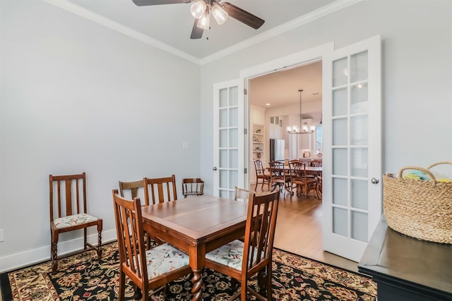 dining room with ceiling fan with notable chandelier, wood-type flooring, ornamental molding, and french doors