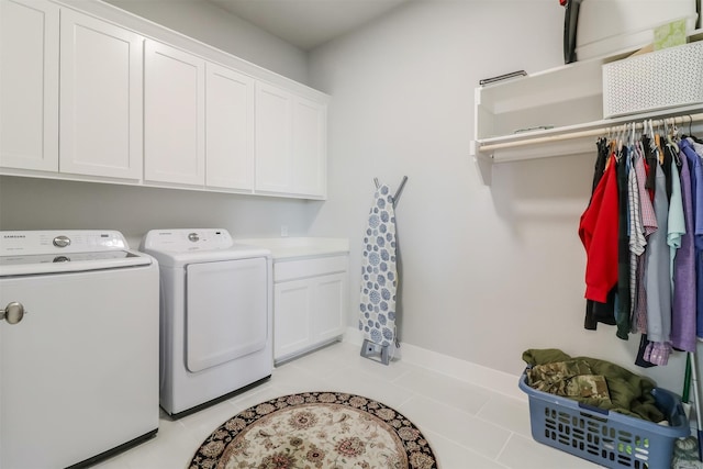 laundry room featuring cabinets, light tile patterned floors, and washer and clothes dryer