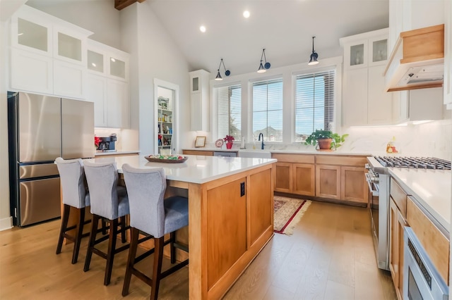 kitchen featuring white cabinets, appliances with stainless steel finishes, a center island, and light hardwood / wood-style floors