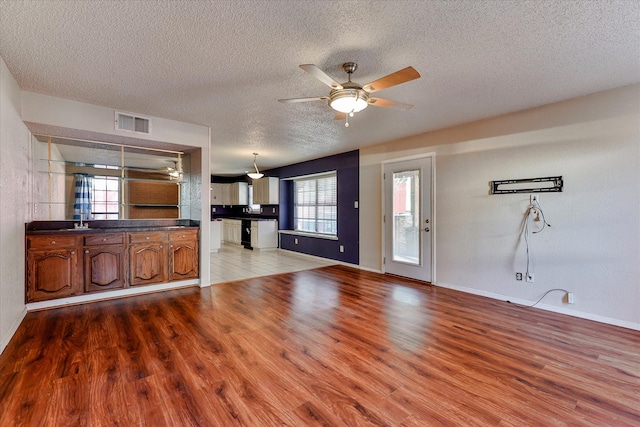 interior space with ceiling fan, a textured ceiling, and light wood-type flooring