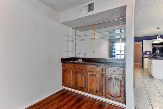 kitchen with sink, electric range oven, hanging light fixtures, a textured ceiling, and tile patterned floors