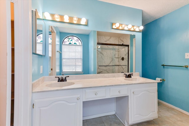 bathroom with a shower with door, vanity, and a textured ceiling