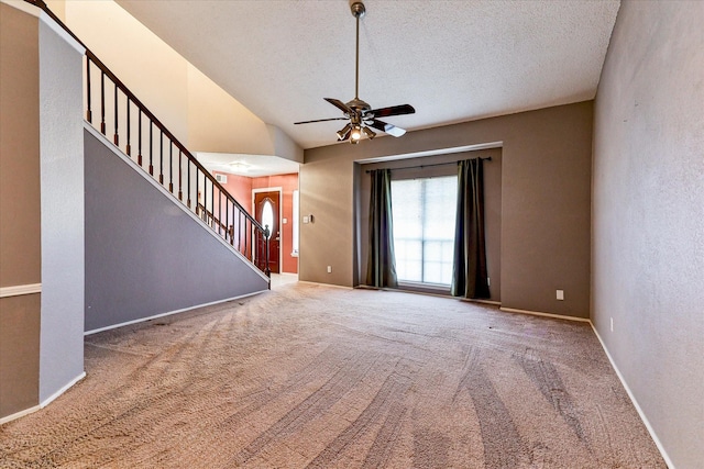 foyer with lofted ceiling, ceiling fan, carpet floors, and a textured ceiling