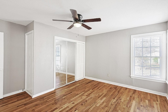 unfurnished bedroom with ceiling fan, a closet, and hardwood / wood-style flooring