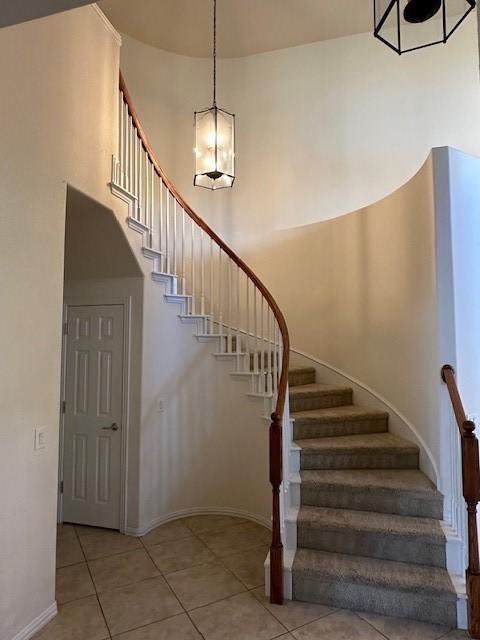 stairs with tile patterned floors and a high ceiling