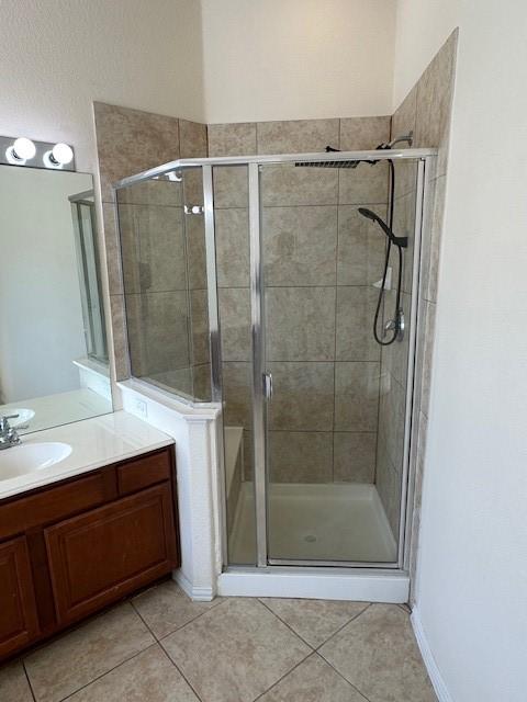 bathroom with walk in shower, vanity, and tile patterned flooring