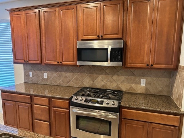 kitchen with backsplash, dark stone counters, and stainless steel appliances