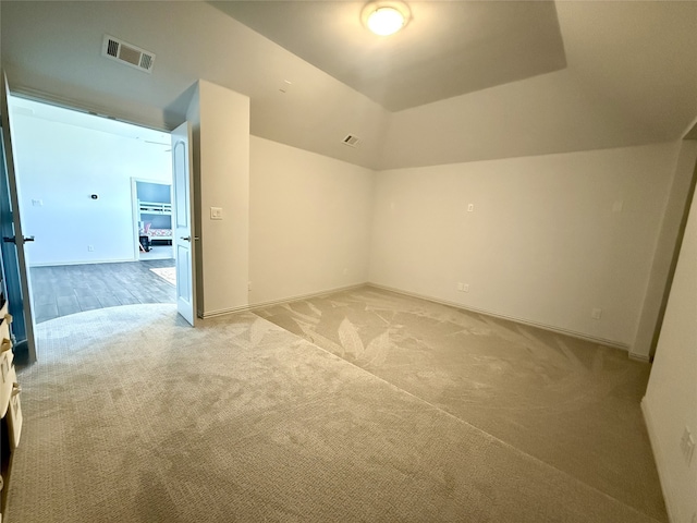 spare room featuring vaulted ceiling and light colored carpet