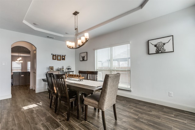 dining space with a tray ceiling and a chandelier