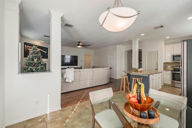 dining space featuring ceiling fan, light tile patterned floors, and ornate columns