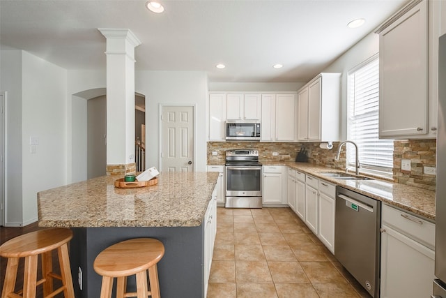 15404 Adlong Dr, Fort Worth, TX 76262 - kitchen with appliances with stainless steel finishes, backsplash, a breakfast bar, light stone countertops, and white cabinetry