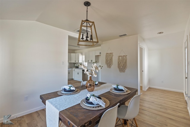 dining area with vaulted ceiling and light hardwood / wood-style flooring