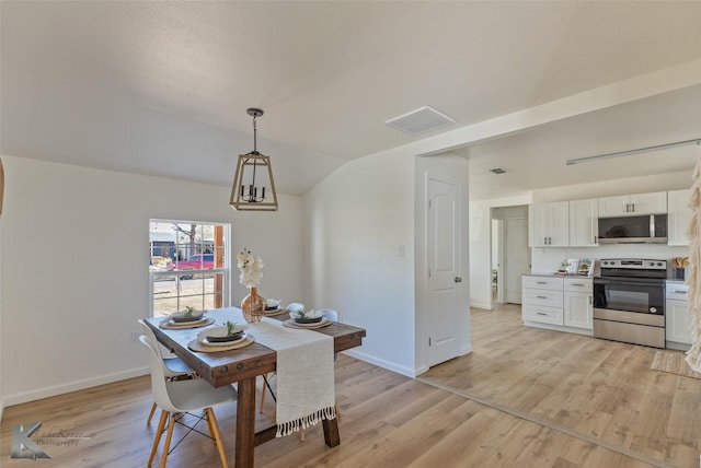 dining room with lofted ceiling and light wood-type flooring