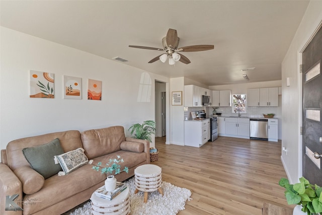 living room featuring ceiling fan and light wood-type flooring