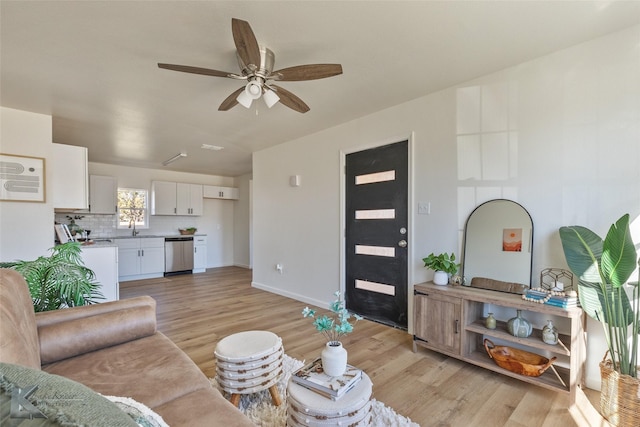 living room with ceiling fan, sink, and light hardwood / wood-style flooring