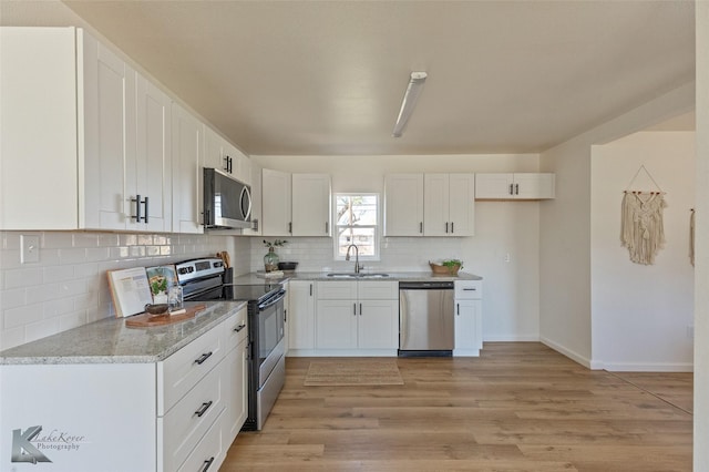 kitchen featuring white cabinets, appliances with stainless steel finishes, light hardwood / wood-style flooring, and sink