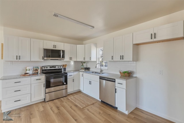 kitchen with white cabinets, stainless steel appliances, light hardwood / wood-style floors, and sink