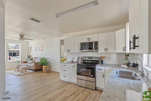 kitchen featuring ceiling fan, sink, light hardwood / wood-style floors, white cabinets, and appliances with stainless steel finishes